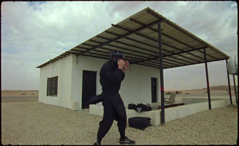 Man next to a house wearing black clothing punching the air in a boxing motion