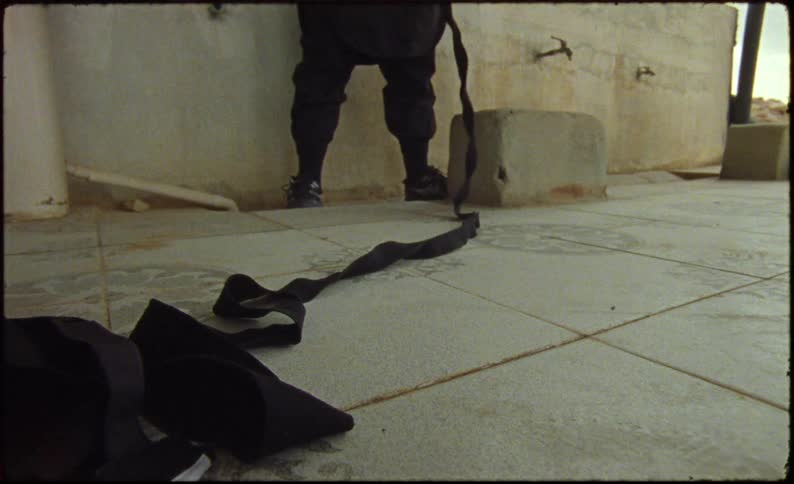 Long black scarf being pulled by a person partially visible in the background