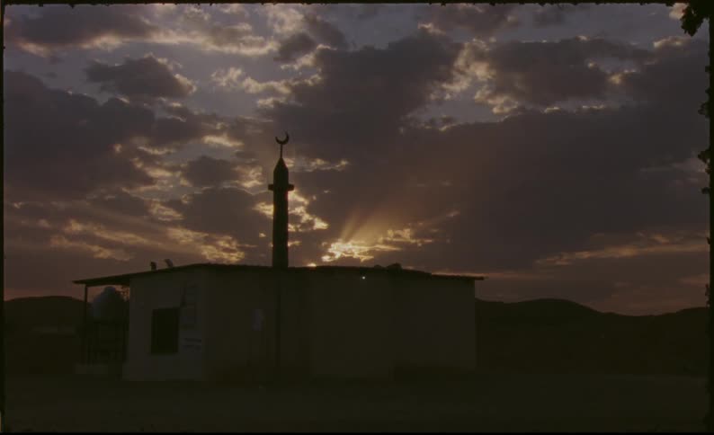 Isolated house in a desert area with the sunset on the horizon