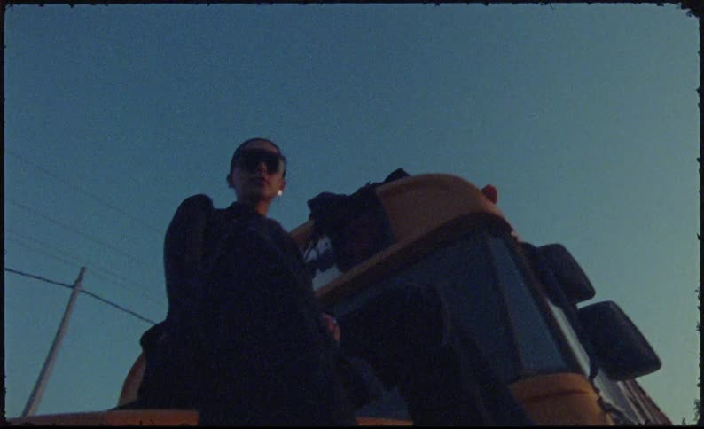 Model woman sitting on the hood of a school bus and putting on a sunglasses