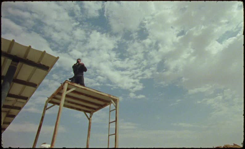The man in black is shadow boxing on a wooden platform that is shaking and rocking as he is moving