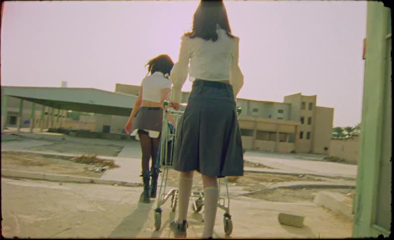 Two models entering an abandoned environment with a shopping cart while both wearing a university uniform