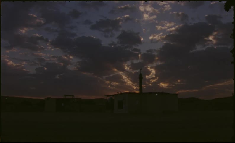 A dramatic sunset over a small building in a desert landscape with clouds in the sky with lightning strikes