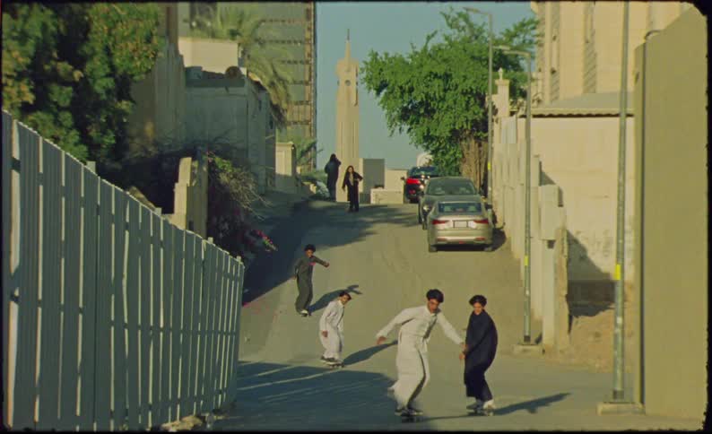 Group of teenagers skateboarding down a narrow street