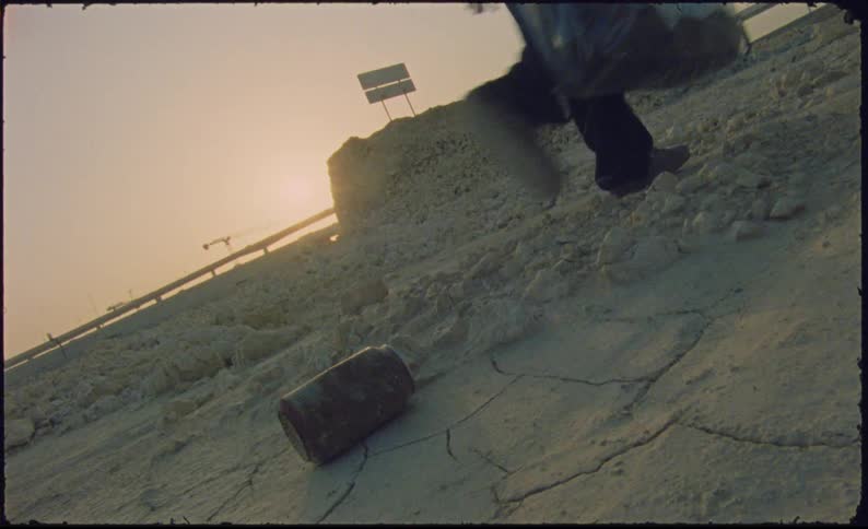 Feet of a person walking on dry ground with a transparent suitcase