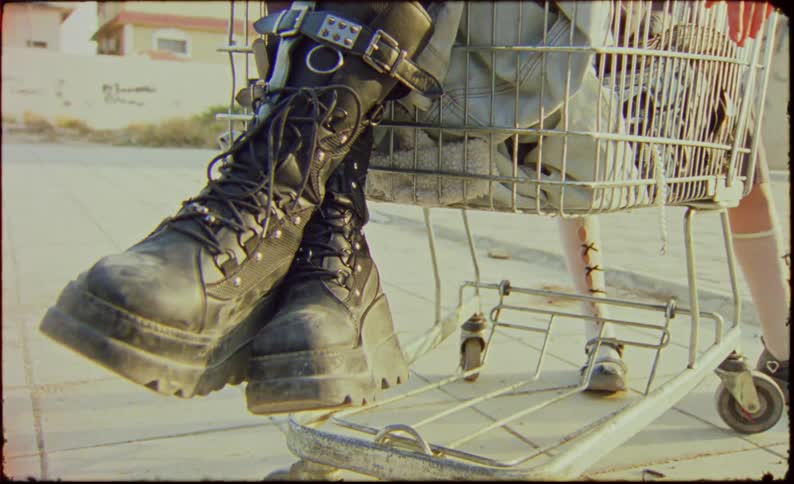 Legs of a woman wearing leather boots sitting in a shopping cart