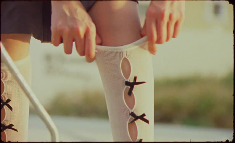 Closeup of a womans legs adjusting a white sock with black laces and on her leg