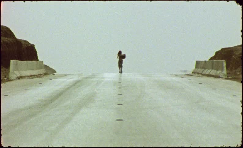 Woman walking on a deserted asphalt road