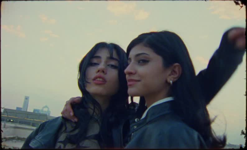 Two young models in leather skirts and jackets on the terrace of a building