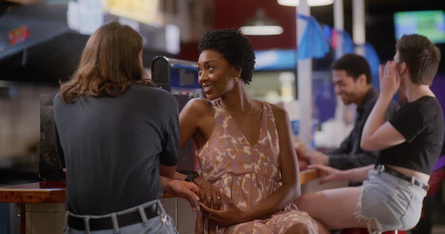 Two dating couples smile and talk while sitting at restaurant counter