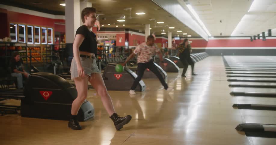 Friends throwing bowling ball and cheering