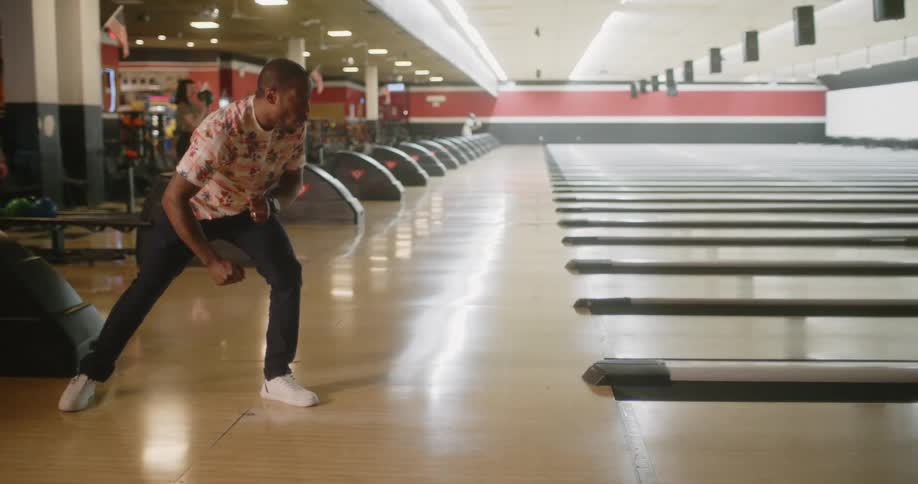 A black man celebrates after bowling