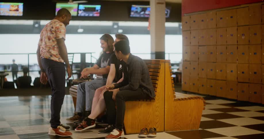 A group of friends are putting on their shoes in a bowling alley