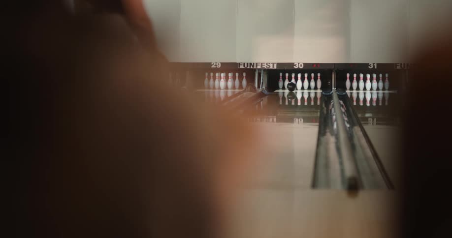 A woman throws the bowling ball down the lane