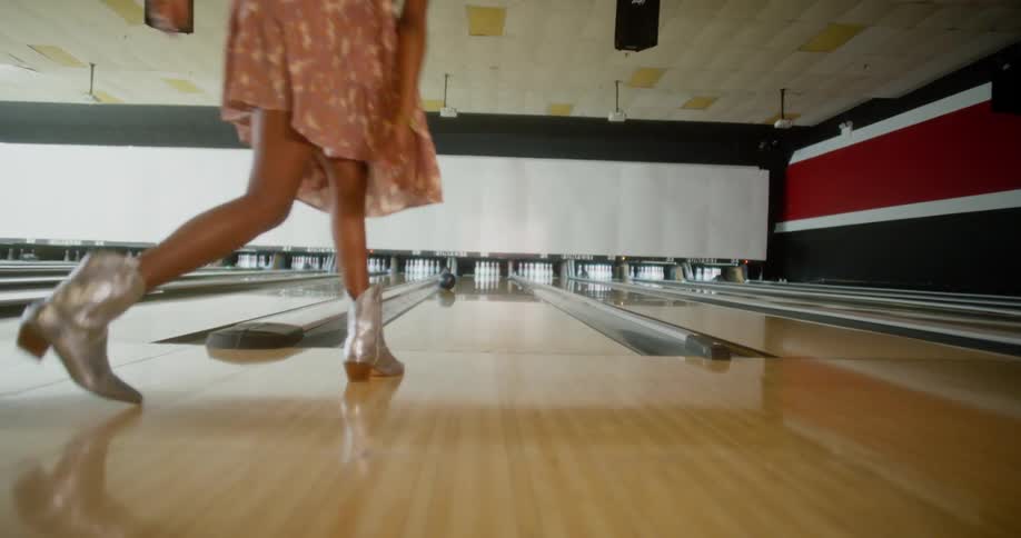 A black woman clicks her heels together and then bowls
