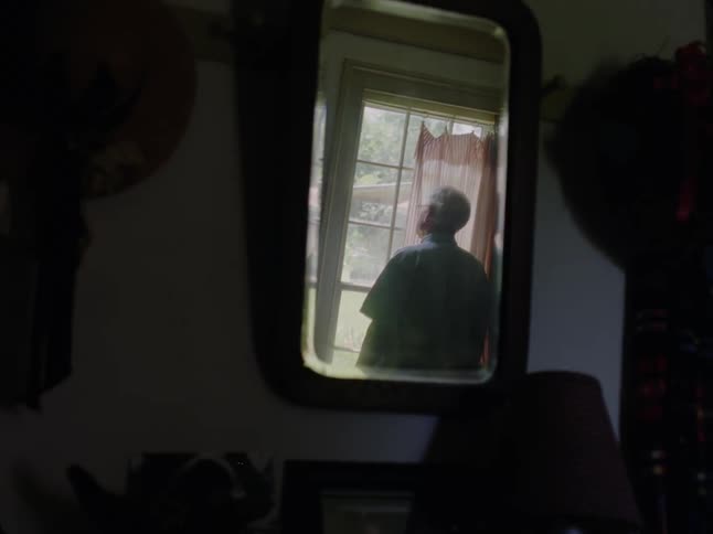 View from a mirror of an elderly man looking through the window