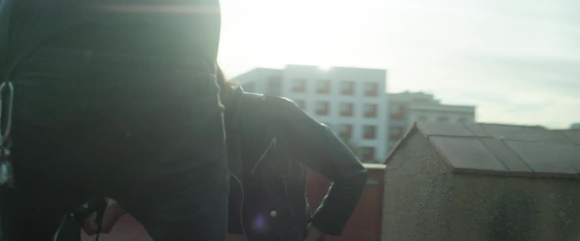 A model and a photographer working on a rooftop then stopping to check the photo on the camera
