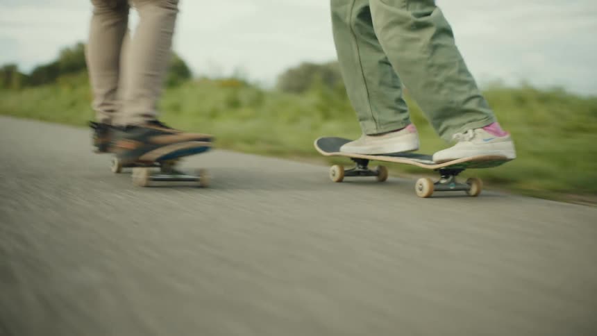 Two people are skateboarding down the path
