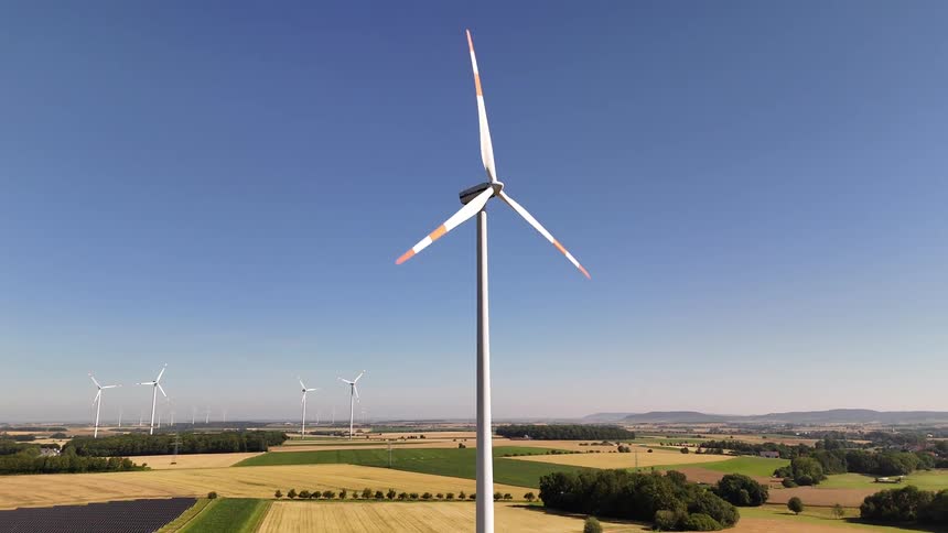 Rotating wind turbine on a wind farm in the countryside casts a shadow on the ground