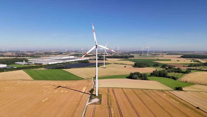Wind turbines spin over agricultural fields