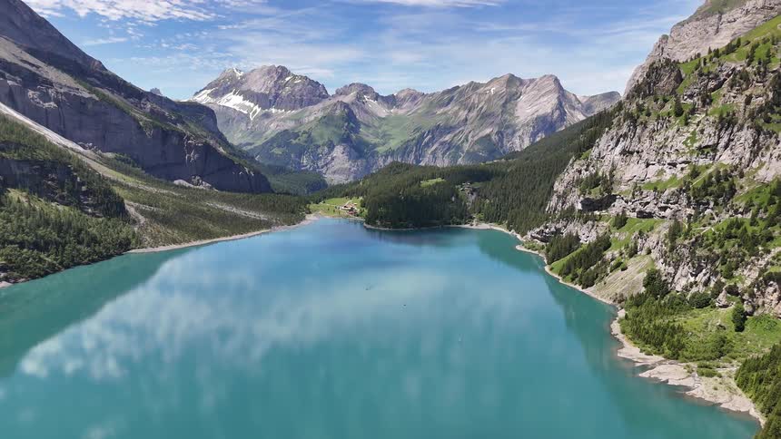 A man stands on a mountain overlooking a large lake below