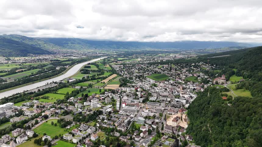 Aerial panorama of an urban city surrounded by mountains and a sea canal on a cloudy day