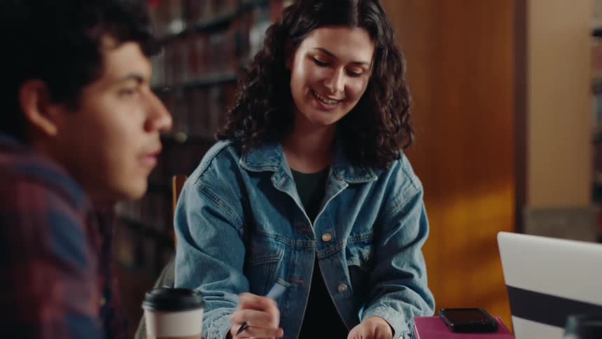 A man and woman talk in a library