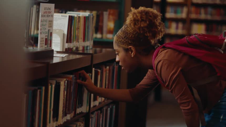 Woman taking a book from a shelf in a library