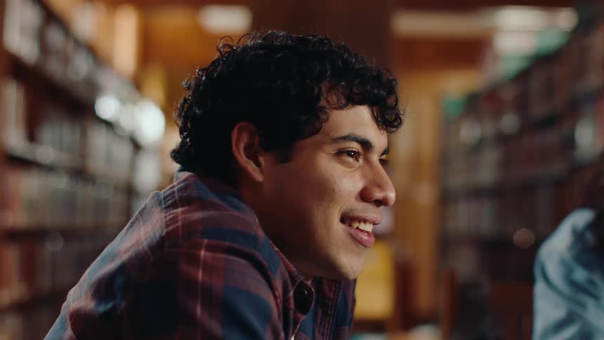 College age people sit in a group in the library and have a discussion