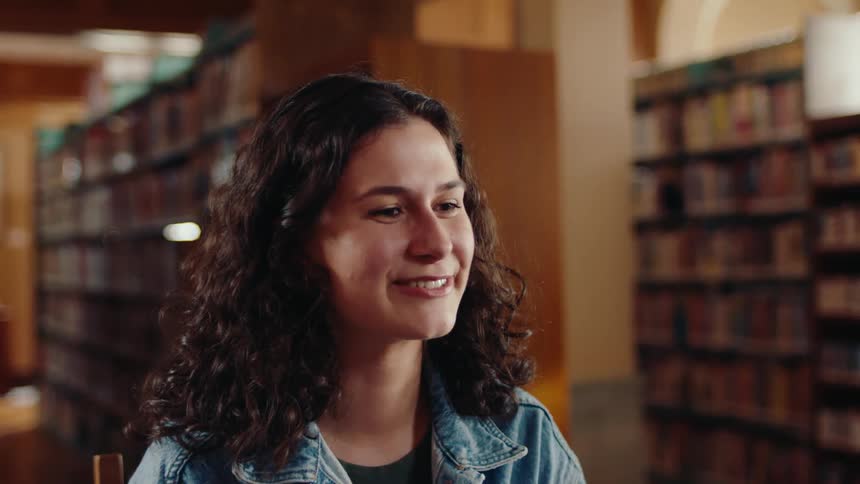 A woman laughs at something off screen in a library