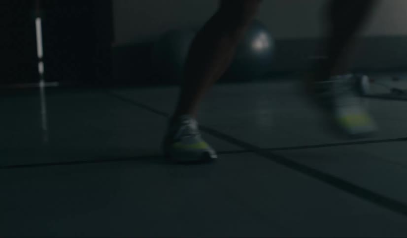 Legs of a person moving indoors with gym equipment warming up