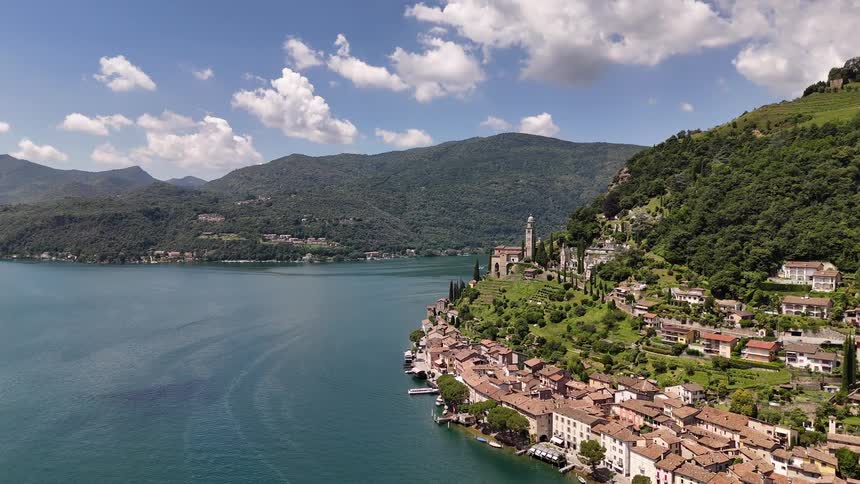 A mid sized city sits on the side of a mountain next to a lake