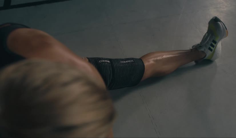 A woman performs a leg stretch in a gym