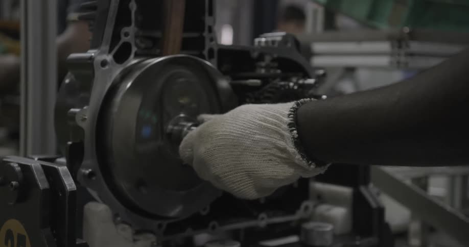 A worker turns a machine crank