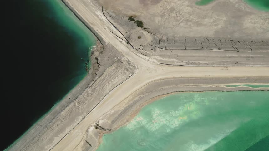 Aerial view of industrial tailings, white sand and bright green water