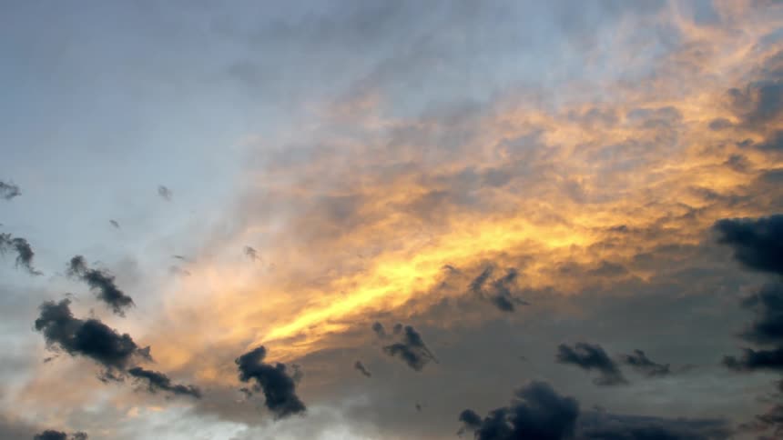 Sunlight shines upon clouds above as small dark clouds move below