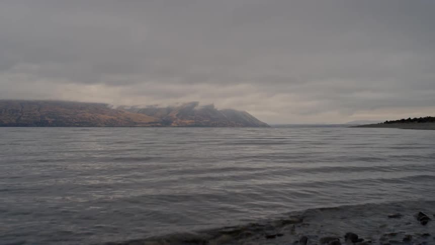 Waves flow onto a rock strewn shore on a misty overcast day