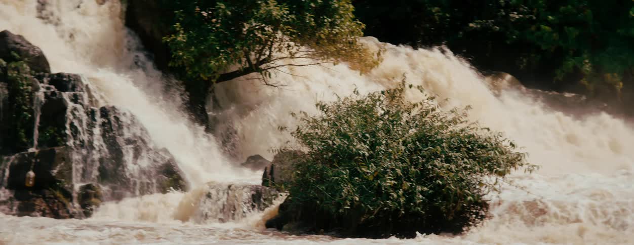 Powerful waterfall cascading over rocks surrounded by lush greenery
