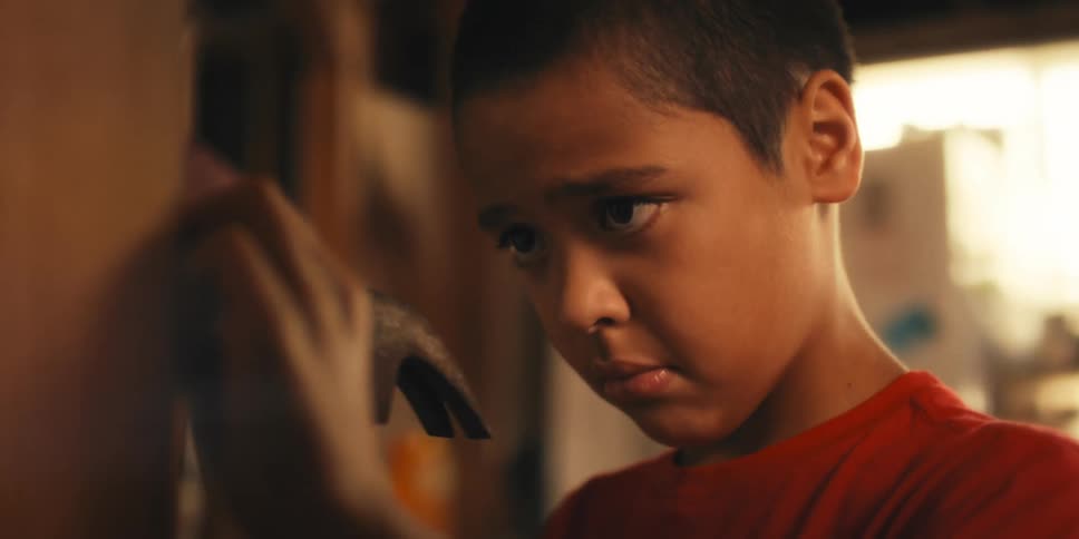 Boy using a hammer and hitting a nail into the wall