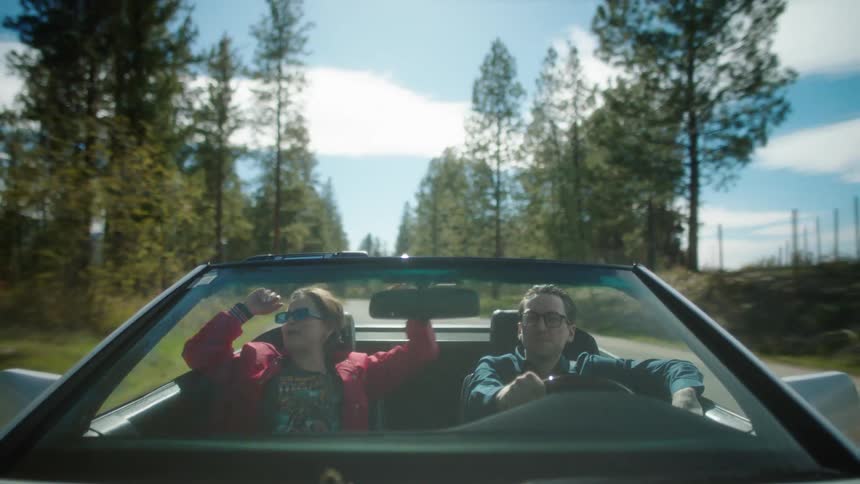 Man and woman traveling in a convertible car