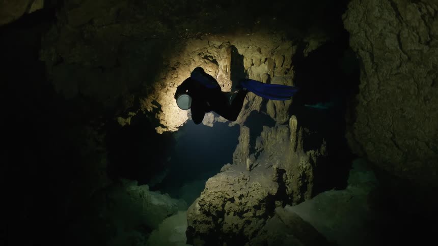 A person in a under water cave illuminated by a single light source