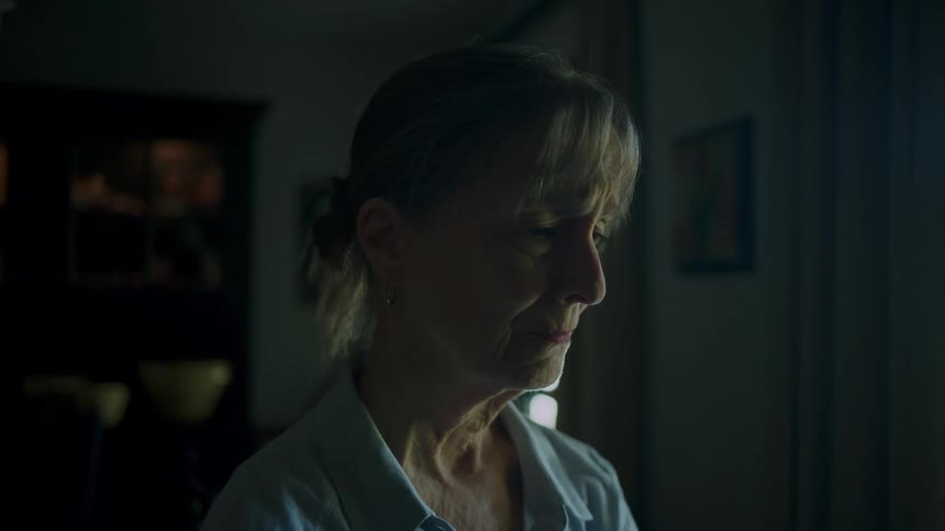 Sad woman stands teary eyed in home