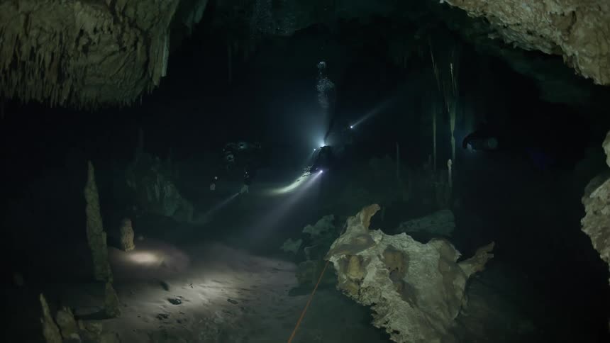 Divers with flashlights inside an aquatic cave