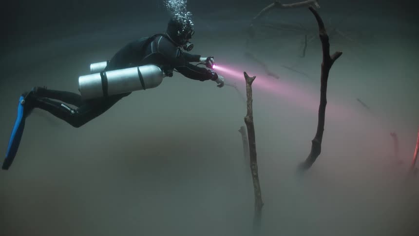 Scuba diver navigates across a patch of underwater fog