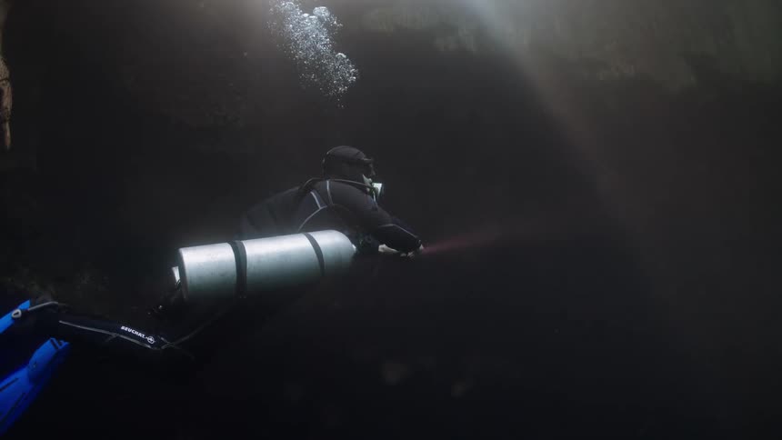 Scuba diver uses a flashlight while exploring an underwater cavern