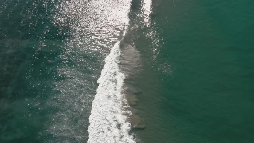 Aerial view of the sea waves with a contrast between the white foam of the waves and the dark blue of the water