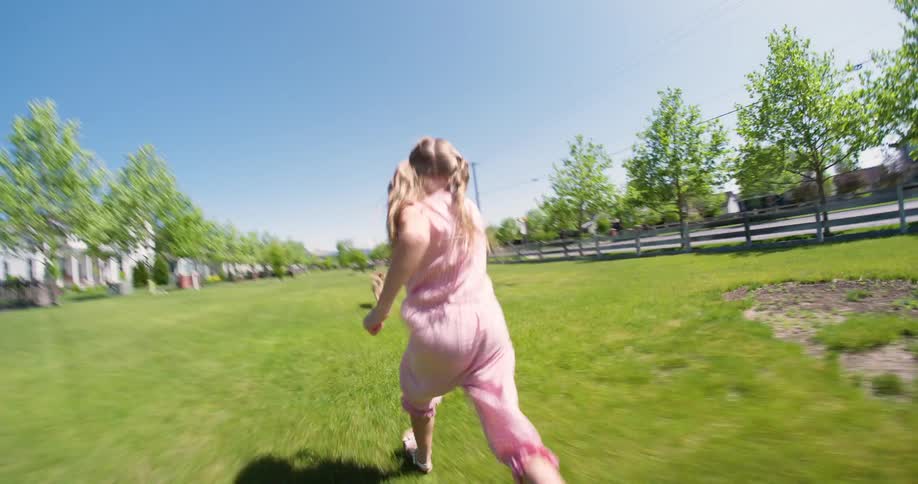 Little girl on the grass running after a dog
