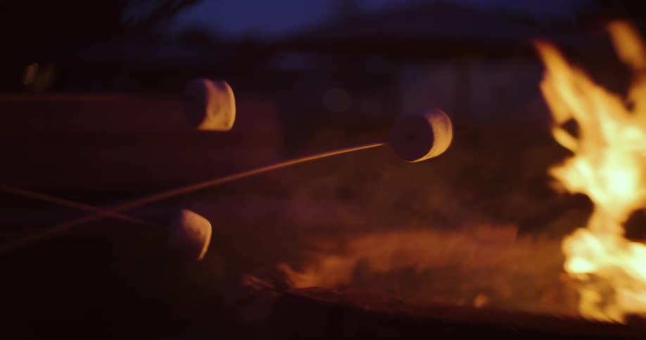 Marshmallows being roasted over a campfire at night