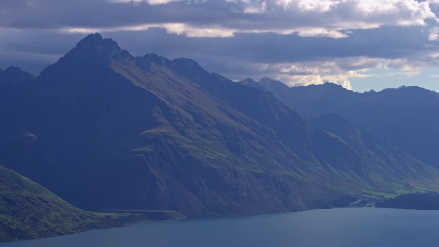 Natural landscape with imposing mountains and a lake at their foot under a partly cloudy sky