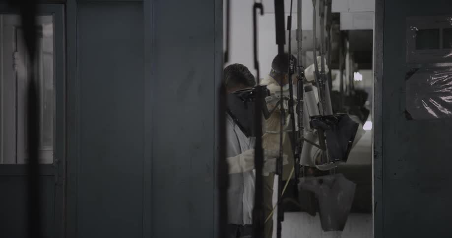 Men work an assembly line in a factory during the day